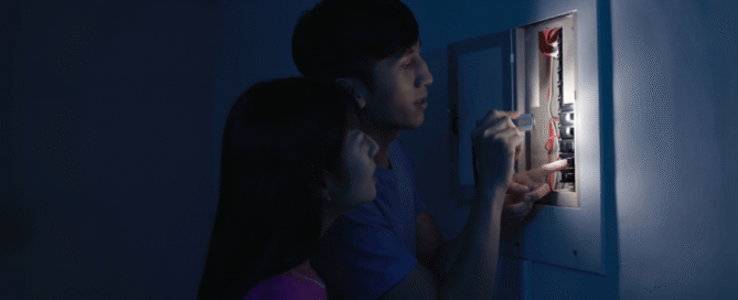 Family checking an electrical panel during a power outage, considering backup generator options from Prescott Valley electrician Assurance Electrical