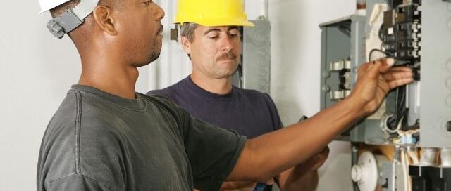 Residential electricians inspecting a home breaker panel during an electrical service call