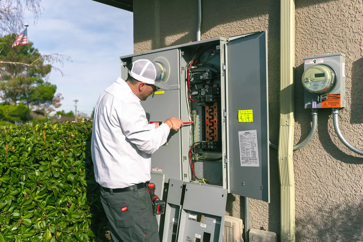 What causes circuit breakers to trip? An electrician inspects an outdoor electrical panel at home today