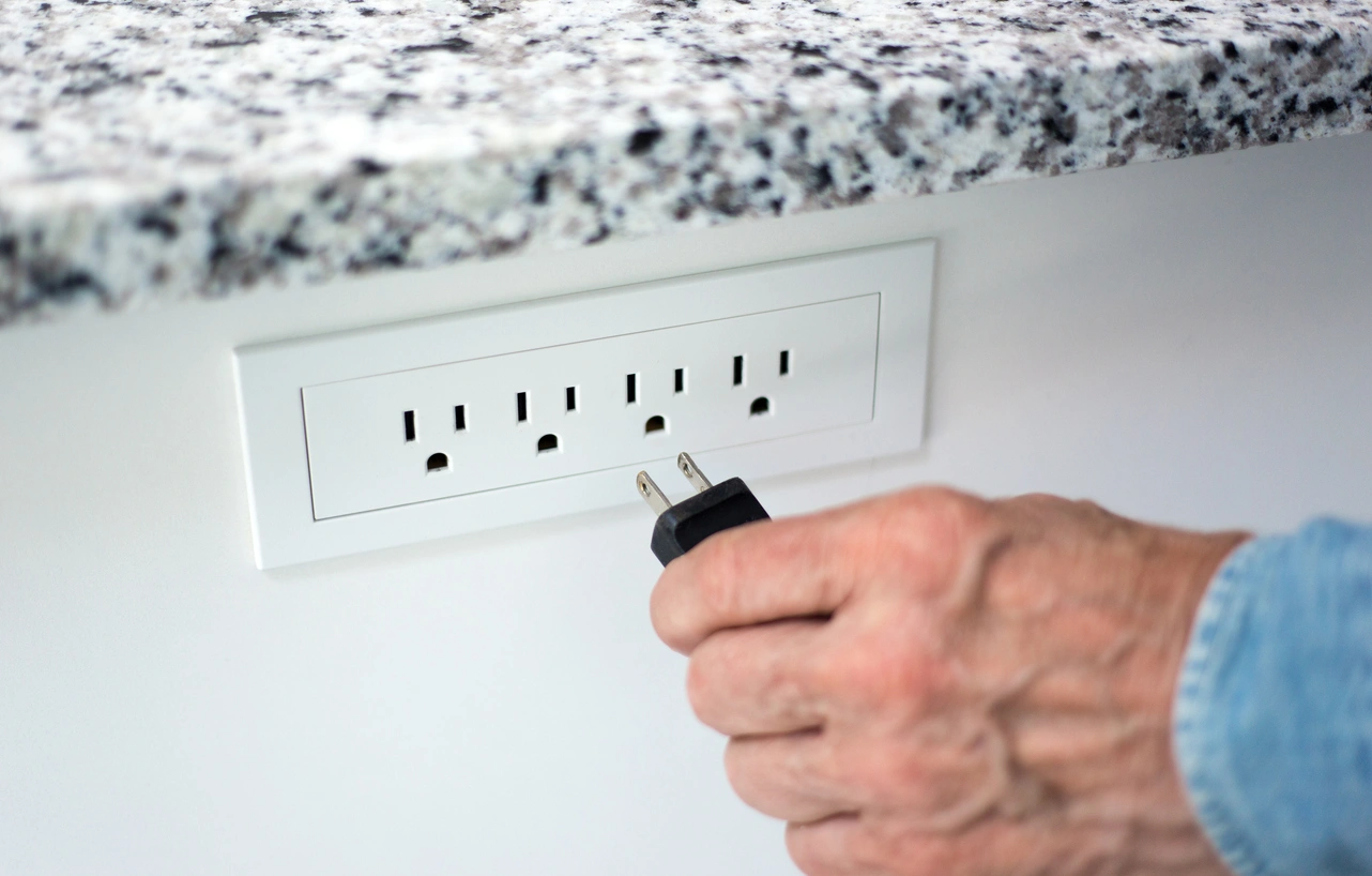 Prescott Valley homeowner plugging into protected outlet after whole house surge protector installation for safer electrical services