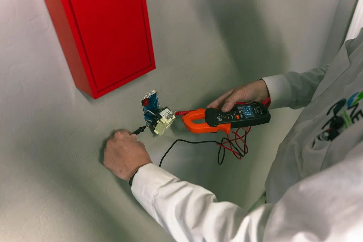 Electrician tests wall wiring with meter, showing signs you need electrical rewiring in Prescott