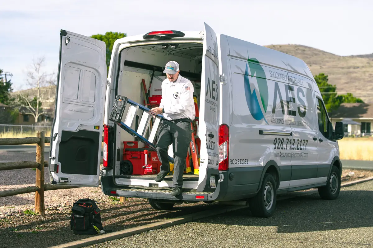 Signs you need to call an electrician: technician unloads ladder and tools from service van outside.