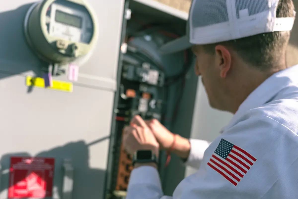 An electrician inspects the breaker box wiring with a tablet, showing on-site electrical panel components.