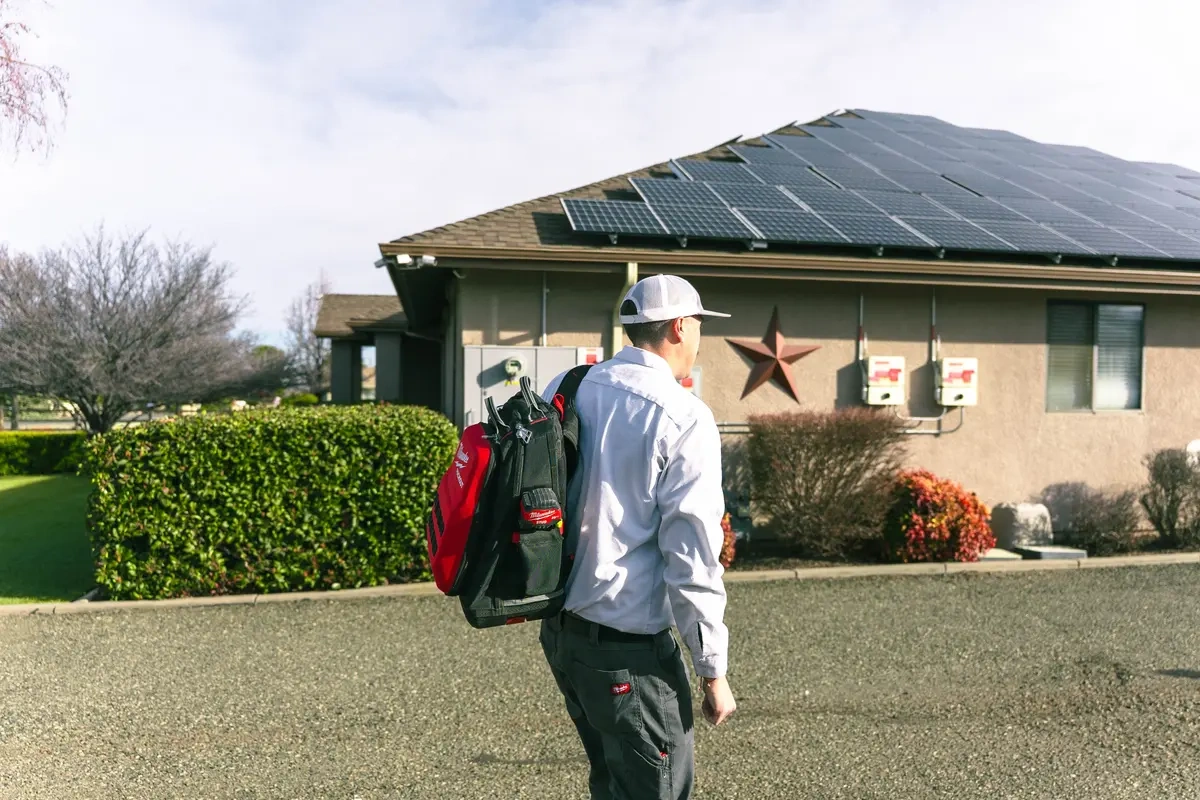 how-to-verify-an-electrician-credentials-door-visit An electrician arrives with tools and a tablet; how to verify an electrician's credentials before hiring.