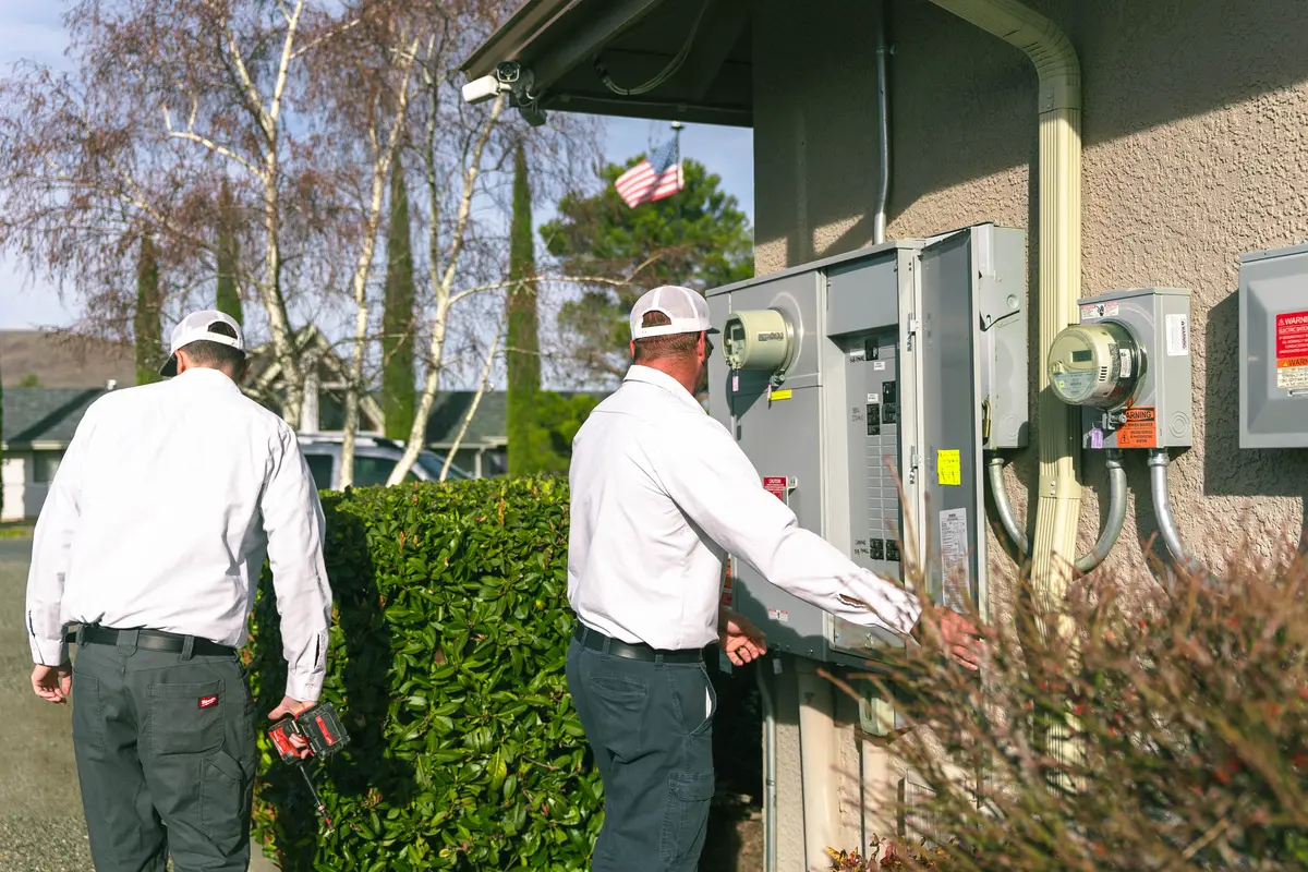 Electricians conducting an electrical system assessment for adding solar panels and batteries.