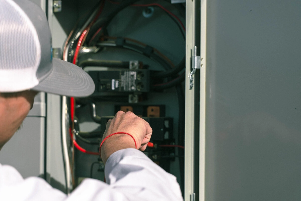 Electrical panel safety tips illustrated by an electrician inspecting wiring and components inside an electrical panel.