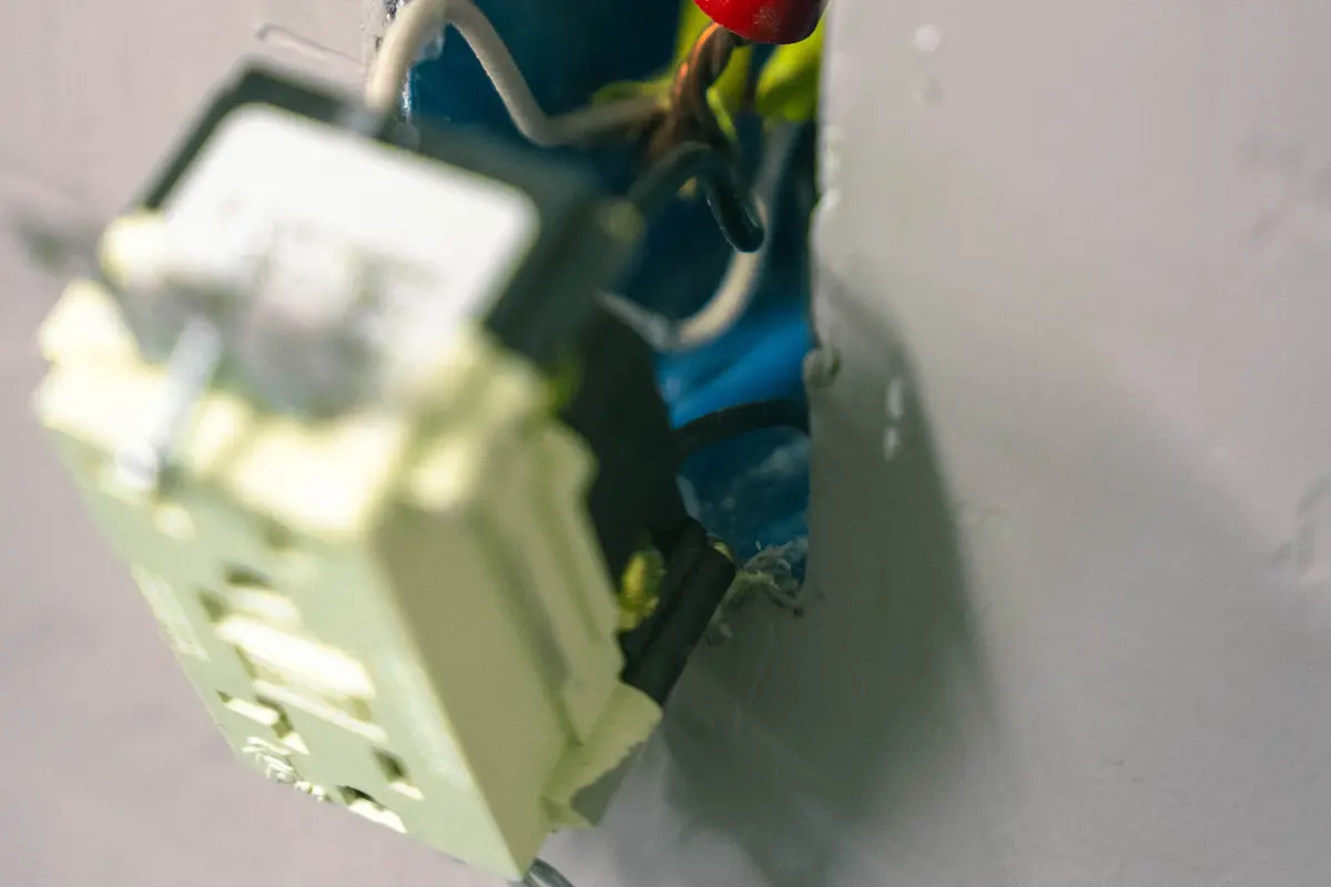 Open electrical outlet showing internal wiring during home surge protection installation to fulfill the main purpose of having surge protection.