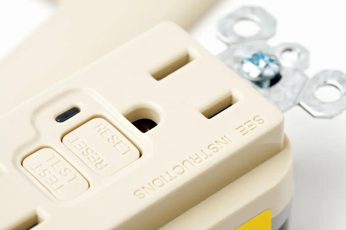 What Is the Difference Between GFCI and AFCI Breakers? White GFCI electrical outlet installed on a wall for home electrical safety and shock protection.